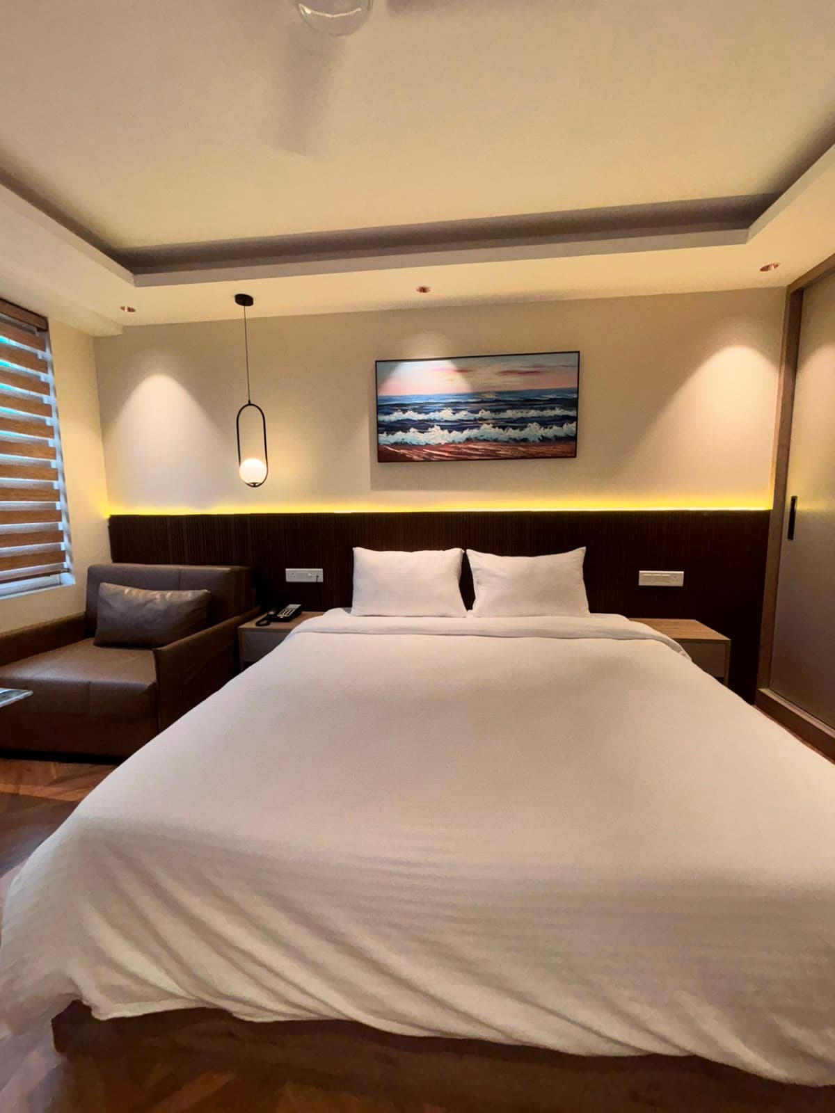 Studio bedroom at Alpha Houz with a king bed, warm cove lighting and framed artwork